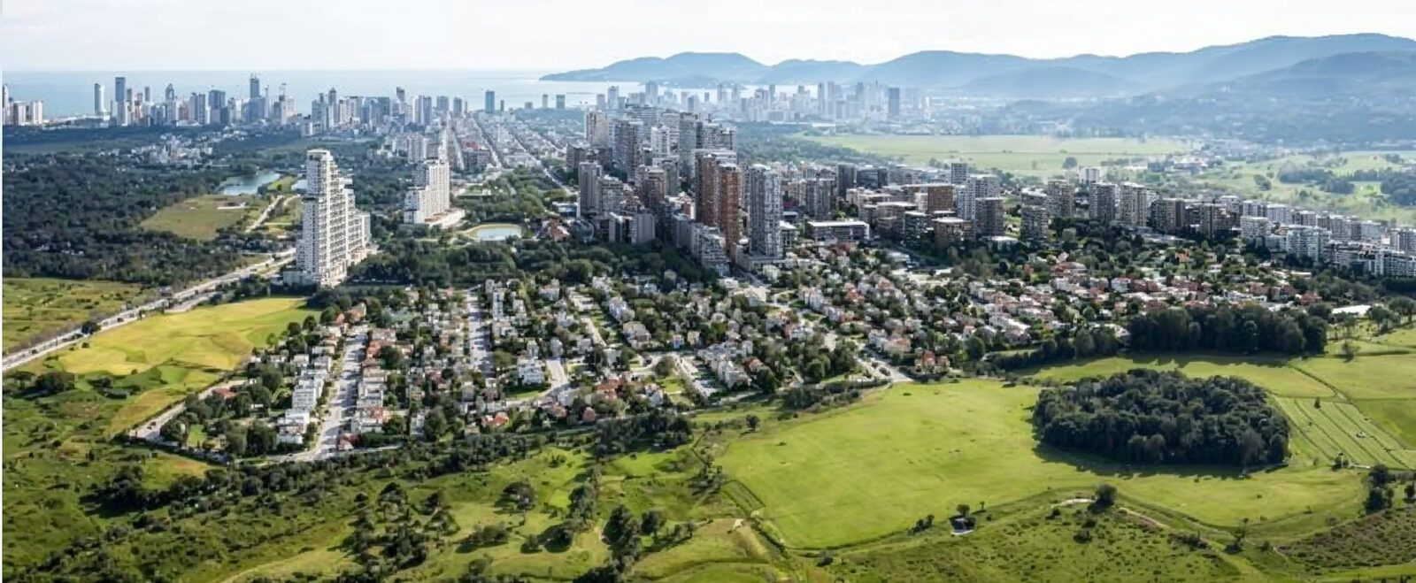 Vista aérea ampla do Vivapark Porto Belo, com as quadras de casas, os prédios e o mar ao fundo